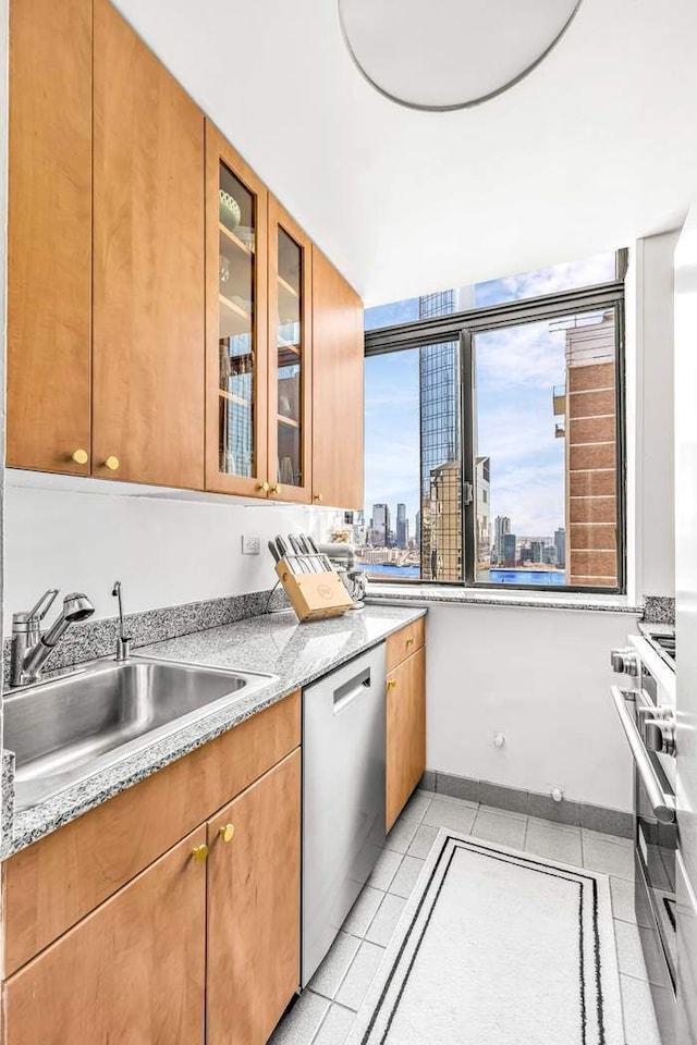 310 E 46th St Unit 19M, New York City, NY 10017 - kitchen featuring stainless steel dishwasher, a sink, stove, a view of skyline, and light tile patterned floors