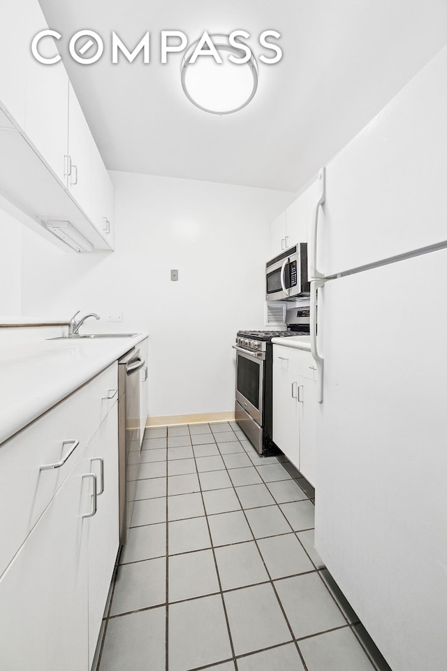 kitchen featuring stainless steel appliances, a sink, light countertops, white cabinets, and light tile patterned flooring