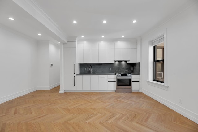 kitchen featuring stainless steel stove, modern cabinets, white cabinets, tasteful backsplash, and baseboards