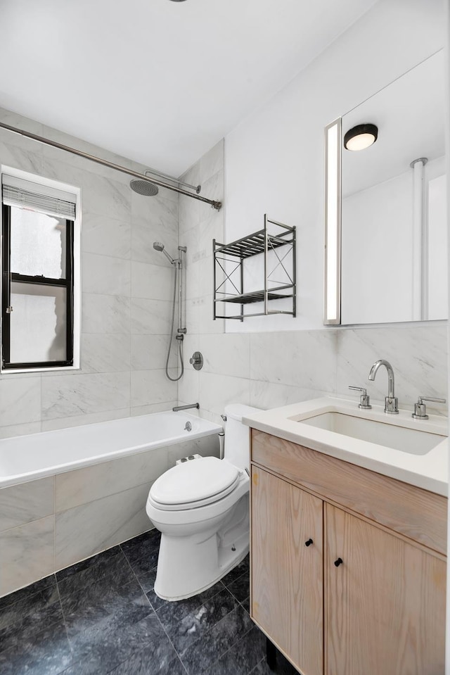 bathroom featuring toilet, tile walls, vanity, and bathtub / shower combination