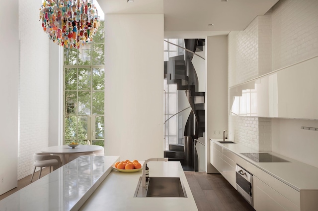 38-40 E 76th St, New York City, NY 10021 - kitchen with black electric stovetop, white cabinetry, dark wood-style floors, and wall oven