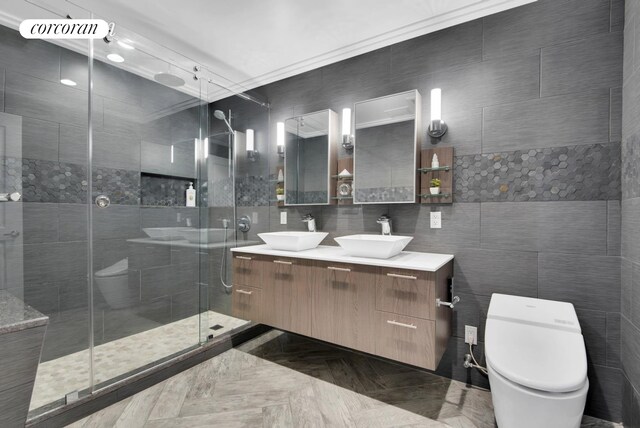 bathroom with double vanity, toilet, a stall shower, and a sink