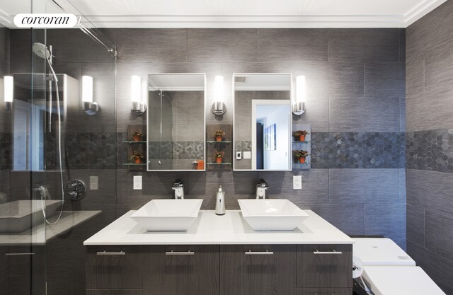 bathroom featuring tile walls, a sink, a shower stall, and double vanity