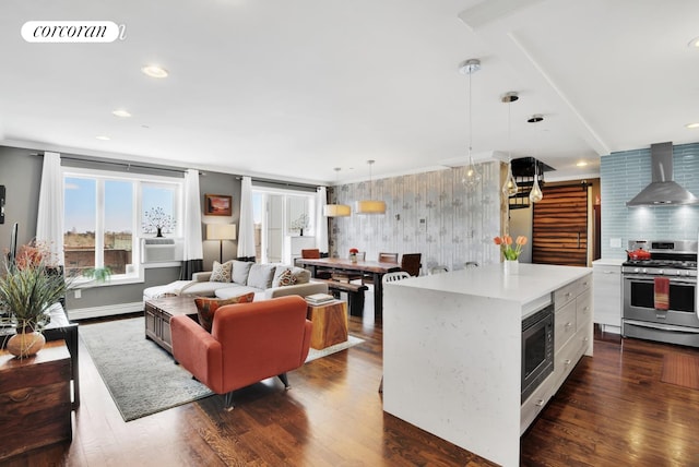kitchen with light countertops, wall chimney range hood, visible vents, appliances with stainless steel finishes, and dark wood-style flooring