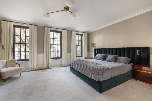 241 E 48th St, New York City, NY 10017 - bedroom featuring ornamental molding, a wainscoted wall, multiple windows, and carpet flooring