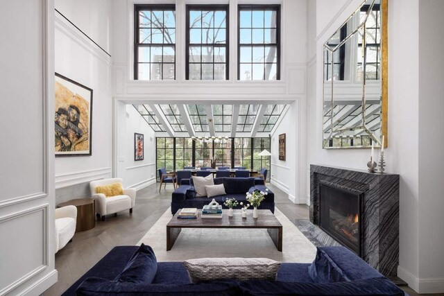 241 E 48th St, New York City, NY 10017 - living room with baseboards, a decorative wall, a high ceiling, and a warm lit fireplace