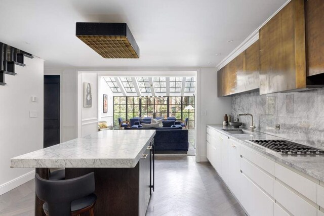 241 E 48th St, New York City, NY 10017 - kitchen featuring tasteful backsplash, a center island, light countertops, stainless steel gas cooktop, and a sink