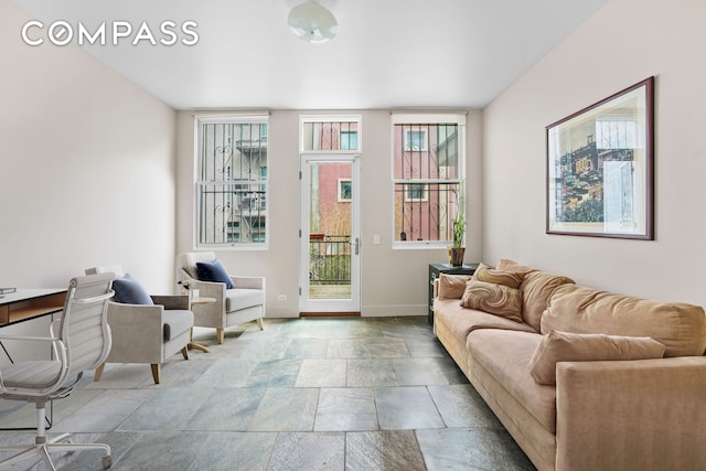living area featuring stone tile flooring and baseboards