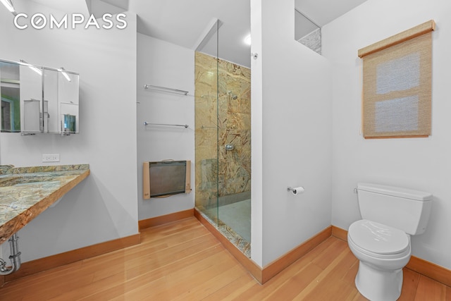 full bathroom with wood finished floors, toilet, baseboards, a sink, and a marble finish shower