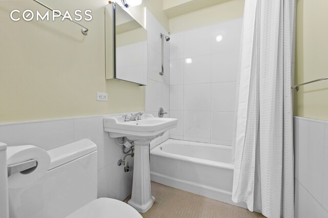 full bathroom featuring toilet, wainscoting, tile walls, shower / tub combo with curtain, and tile patterned flooring