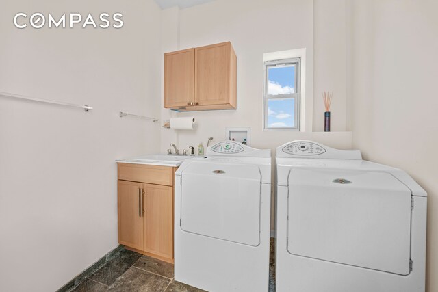clothes washing area with separate washer and dryer, a sink, and cabinet space
