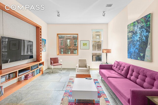 living room featuring baseboards and stone tile floors
