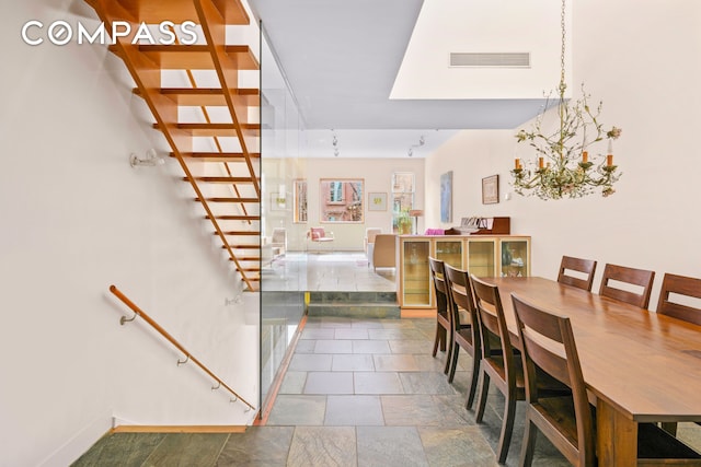 dining area featuring visible vents, stone finish floor, a notable chandelier, and stairway