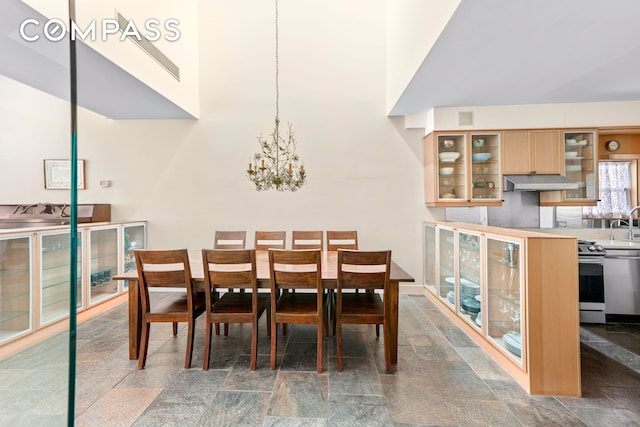 dining area with visible vents, stone finish flooring, a high ceiling, and an inviting chandelier