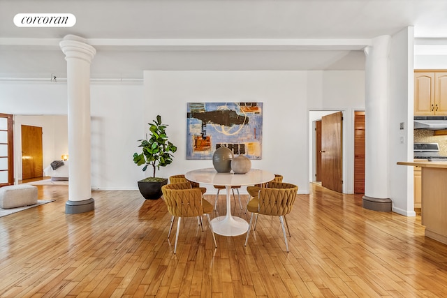 dining room featuring ornate columns and light wood-style floors