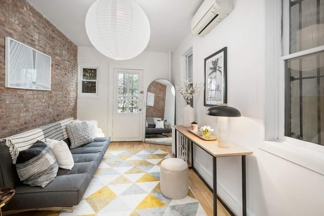 315 W 71st St, New York City, NY 10023 - living area featuring a wall mounted AC, arched walkways, brick wall, and light wood-type flooring
