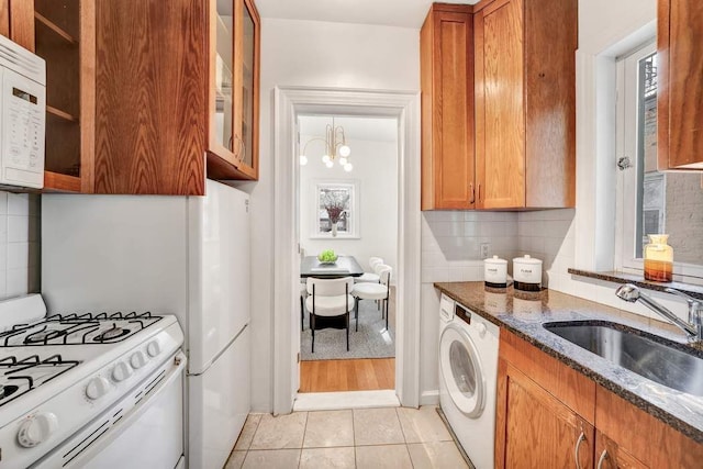 315 W 71st St, New York City, NY 10023 - kitchen with washer / dryer, a sink, white appliances, dark stone counters, and tasteful backsplash