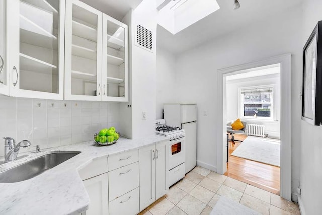 315 W 71st St, New York City, NY 10023 - kitchen with radiator, gas range gas stove, a sink, backsplash, and white cabinets