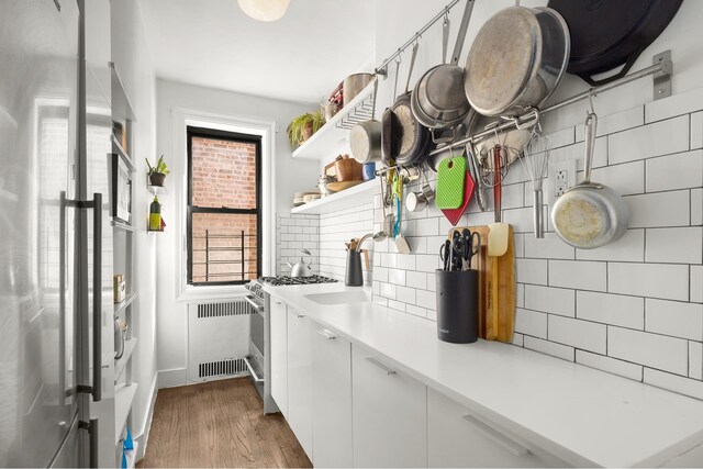 192 E 8th St Unit 6A, New York City, NY 11218 - washroom featuring dark wood finished floors, baseboards, a sink, and radiator heating unit
