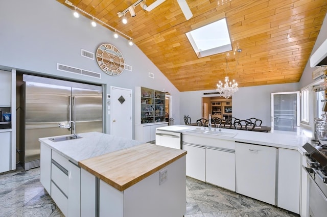 kitchen with an inviting chandelier, visible vents, a skylight, dishwasher, and wood counters