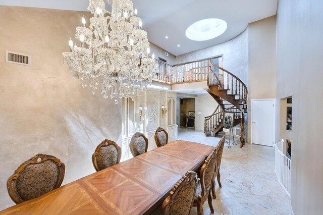 dining space featuring visible vents, stairway, a notable chandelier, and a towering ceiling