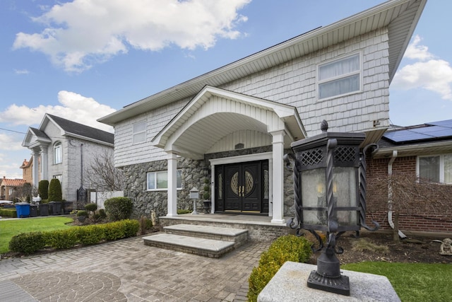 exterior space featuring stone siding and roof mounted solar panels