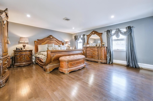 bedroom featuring baseboards, visible vents, multiple windows, and hardwood / wood-style floors