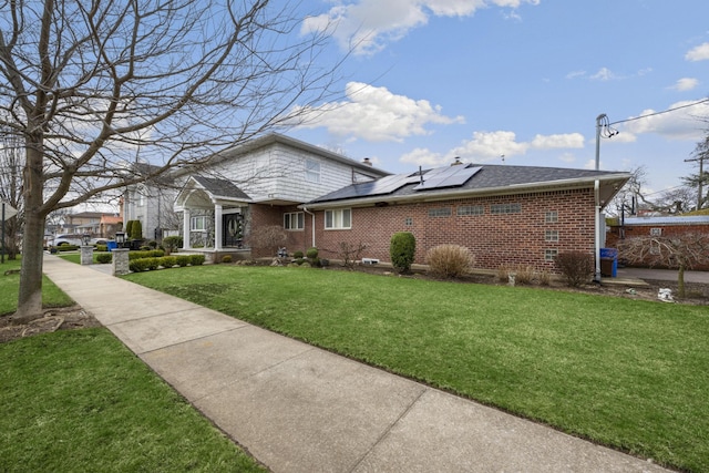 exterior space with a front yard, brick siding, and solar panels