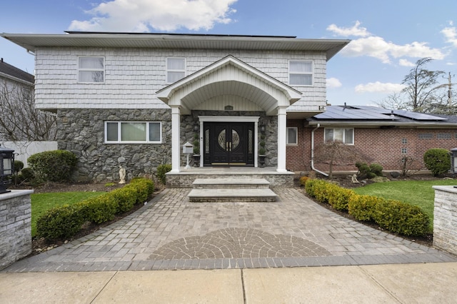 view of front of house featuring stone siding and solar panels