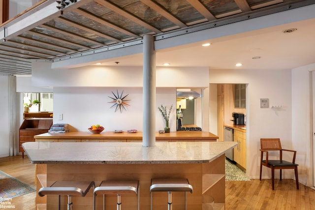 77 Bleecker St Unit 520, New York City, NY 10012 - kitchen with light wood-type flooring, recessed lighting, stainless steel dishwasher, light stone counters, and a center island
