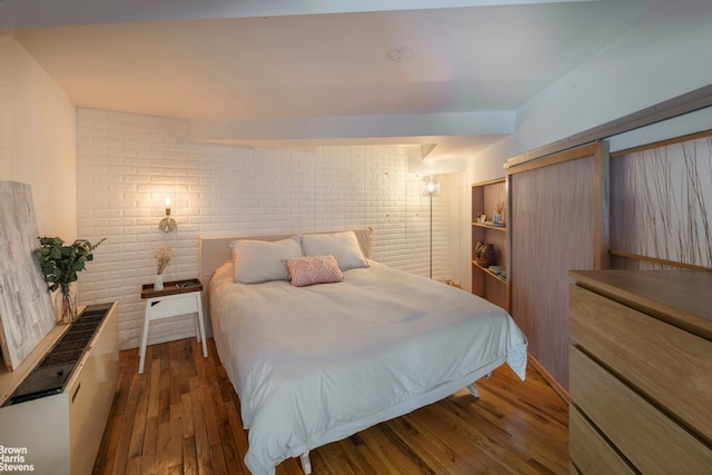 77 Bleecker St Unit 520, New York City, NY 10012 - bedroom featuring brick wall and wood finished floors