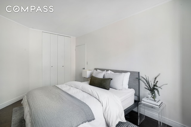 bedroom featuring baseboards, wood finished floors, and a closet