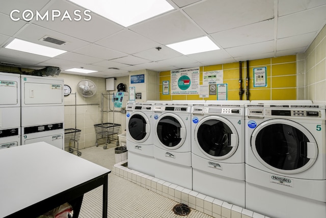 communal laundry room with stacked washer and clothes dryer, tile walls, and independent washer and dryer
