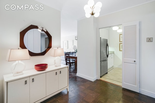 hallway with crown molding, baseboards, and a chandelier