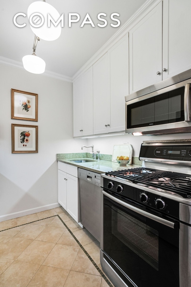 kitchen with crown molding, appliances with stainless steel finishes, a sink, baseboards, and light tile patterned floors