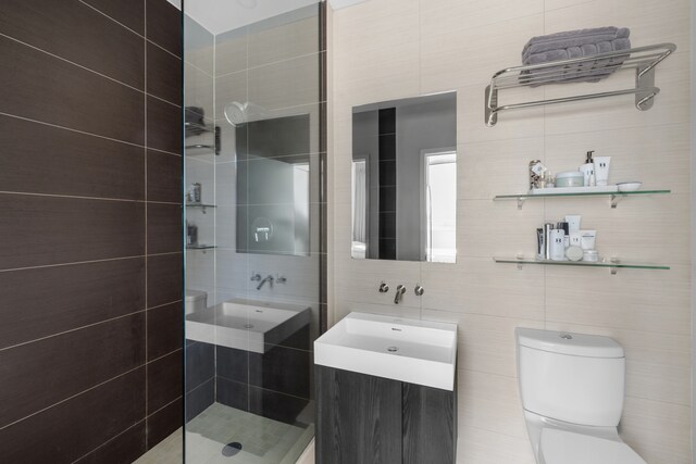 full bath featuring a stall shower, toilet, tile walls, and vanity