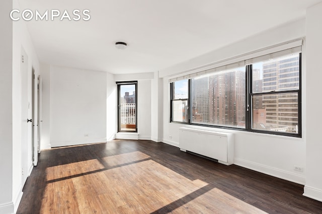 empty room featuring radiator, baseboards, and wood finished floors