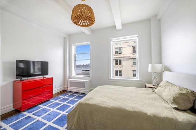 bedroom with beam ceiling, baseboards, and wood finished floors