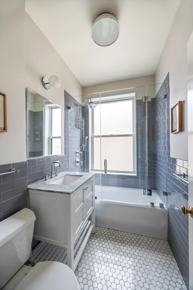 full bathroom featuring tile walls, toilet, tub / shower combination, plenty of natural light, and tile patterned floors