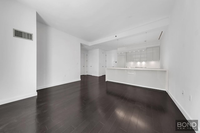 300 E 23rd St Unit 7H, New York City, NY 10010 - unfurnished living room featuring dark wood-style floors and baseboards