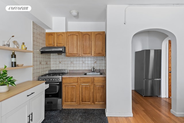 240 E 24th St Unit 1E, New York City, NY 10010 - kitchen with freestanding refrigerator, range with gas cooktop, under cabinet range hood, open shelves, and tasteful backsplash