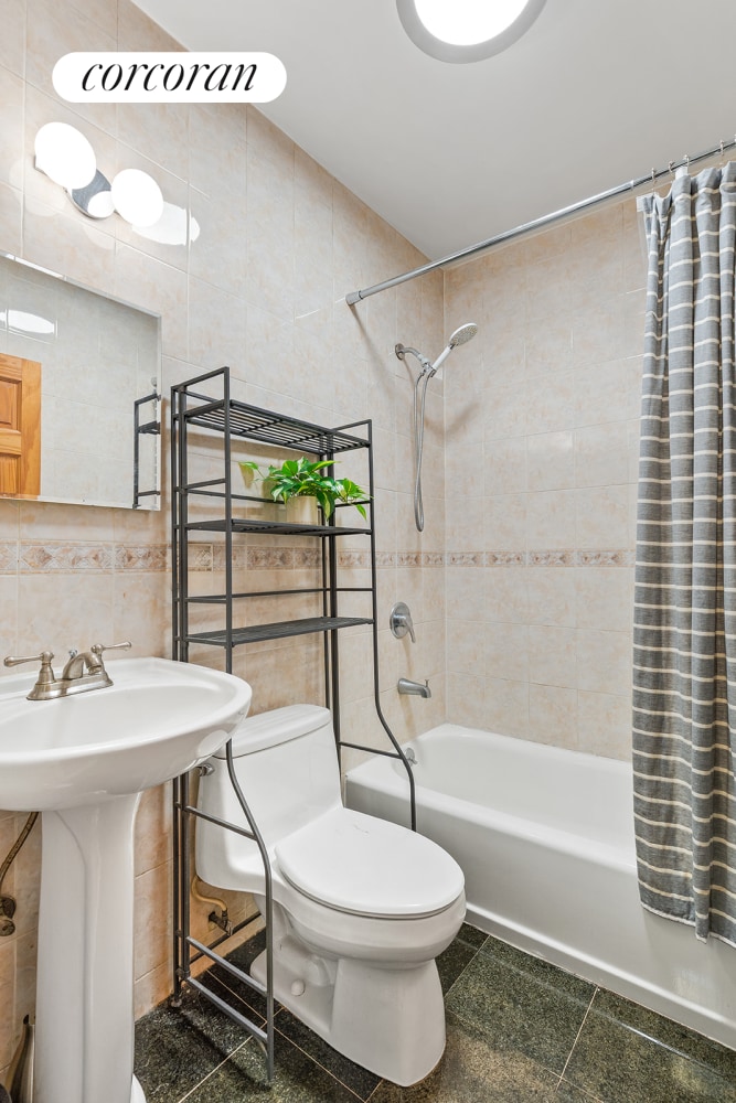 240 E 24th St Unit 1E, New York City, NY 10010 - full bathroom featuring tile walls, toilet, shower / bath combination with curtain, and a sink