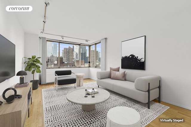 living area with rail lighting, light wood-style flooring, and a skyline view
