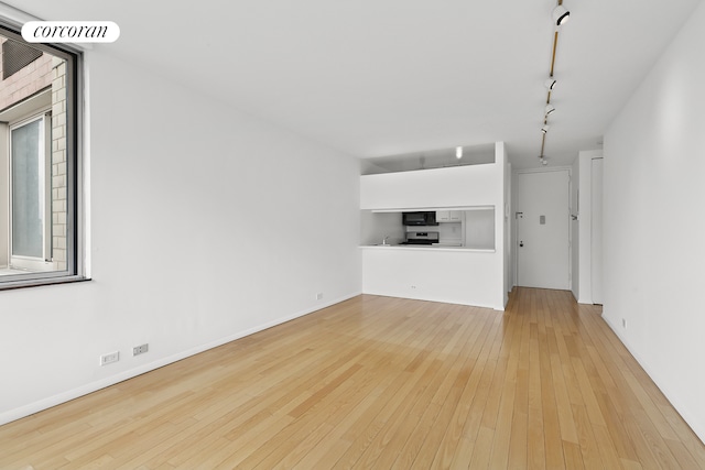 unfurnished living room featuring hardwood / wood-style floors, rail lighting, and baseboards