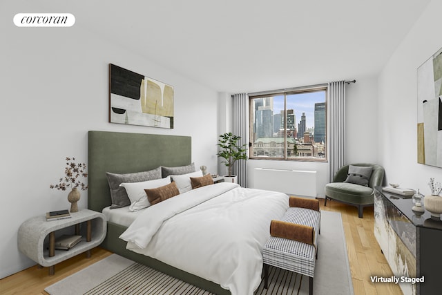 bedroom with light wood finished floors and a view of skyline