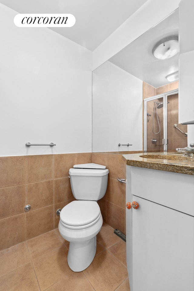 bathroom featuring tile walls, vanity, toilet, a stall shower, and tile patterned flooring