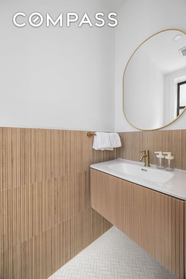 bathroom with visible vents, wainscoting, and a sink