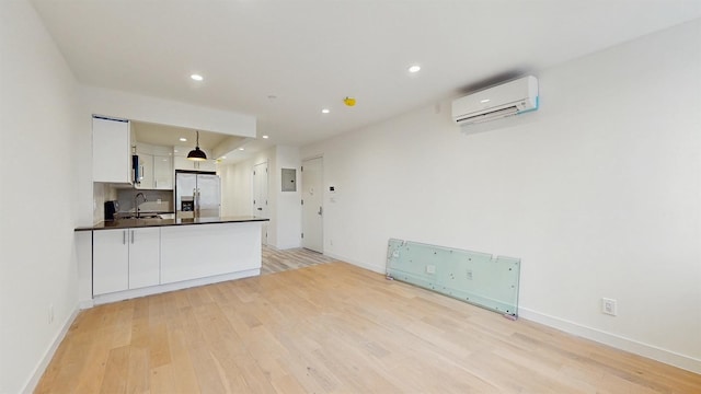 800 5th Ave Unit 1A, New York City, NY 11232 - kitchen with stainless steel fridge, a wall mounted air conditioner, a sink, dark countertops, and white cabinets