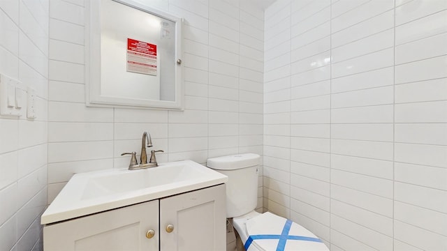 half bathroom with vanity, tile walls, and toilet