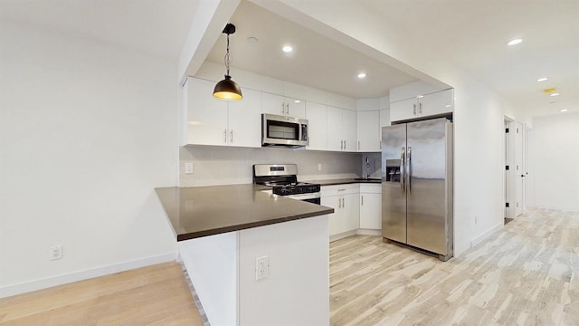 kitchen featuring a peninsula, light wood-style flooring, backsplash, dark countertops, and stainless steel appliances